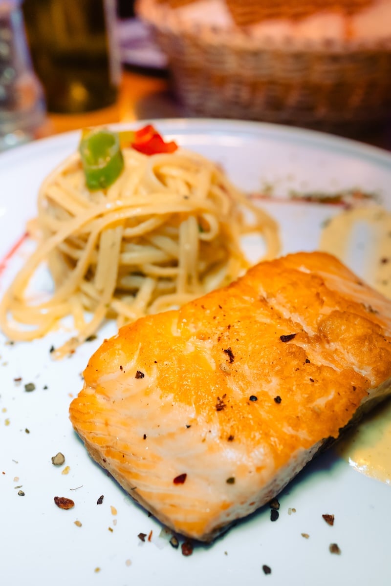 Das Bild zeigt Pasta und Lachs, geschmackvoll angerichtet im Restaurant Al Porto in Rostock.
